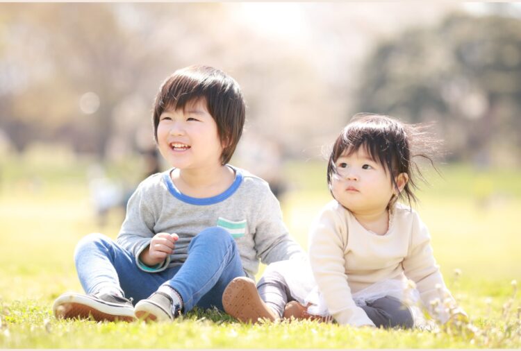 公園の芝生に並んで座って、笑顔で過ごす子どもたち