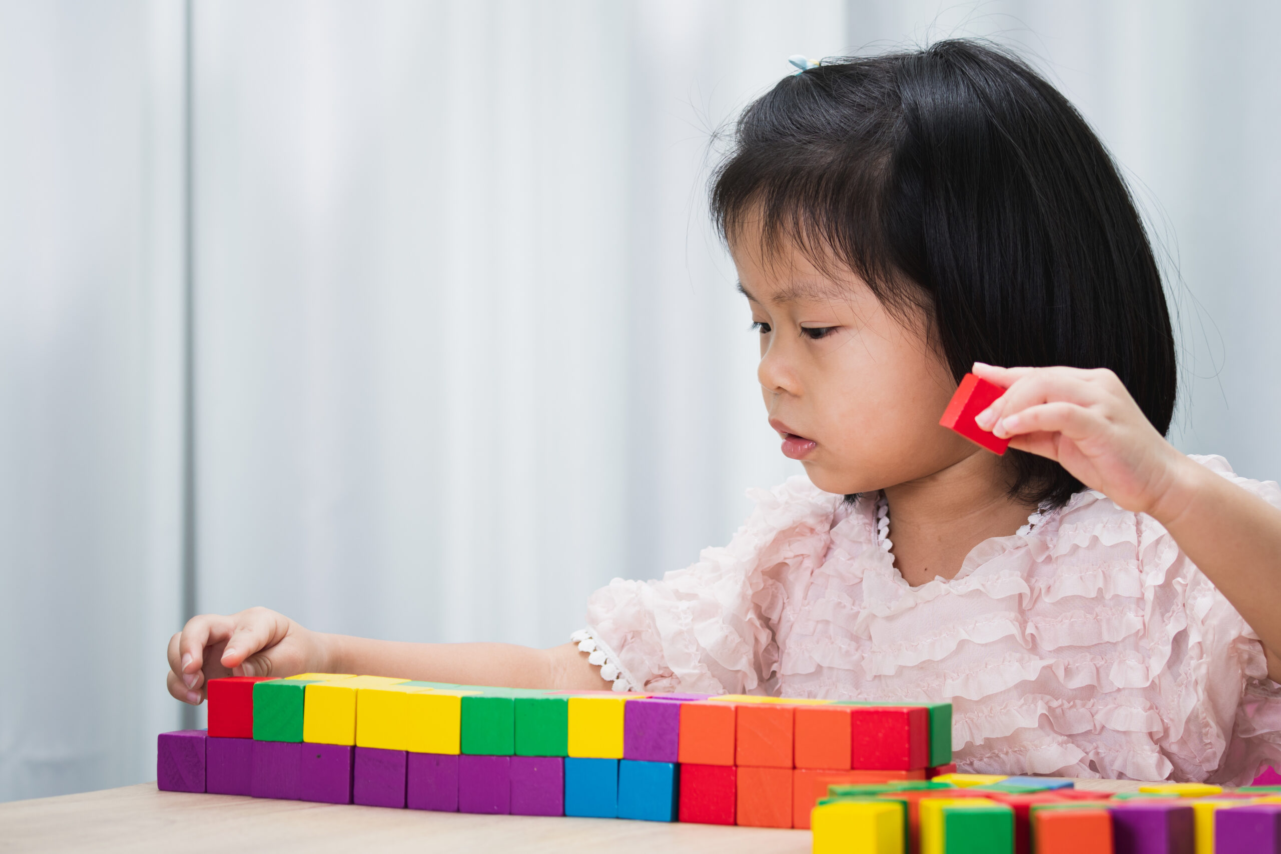 カラフルな積み木で、集中して遊んでいる女の子